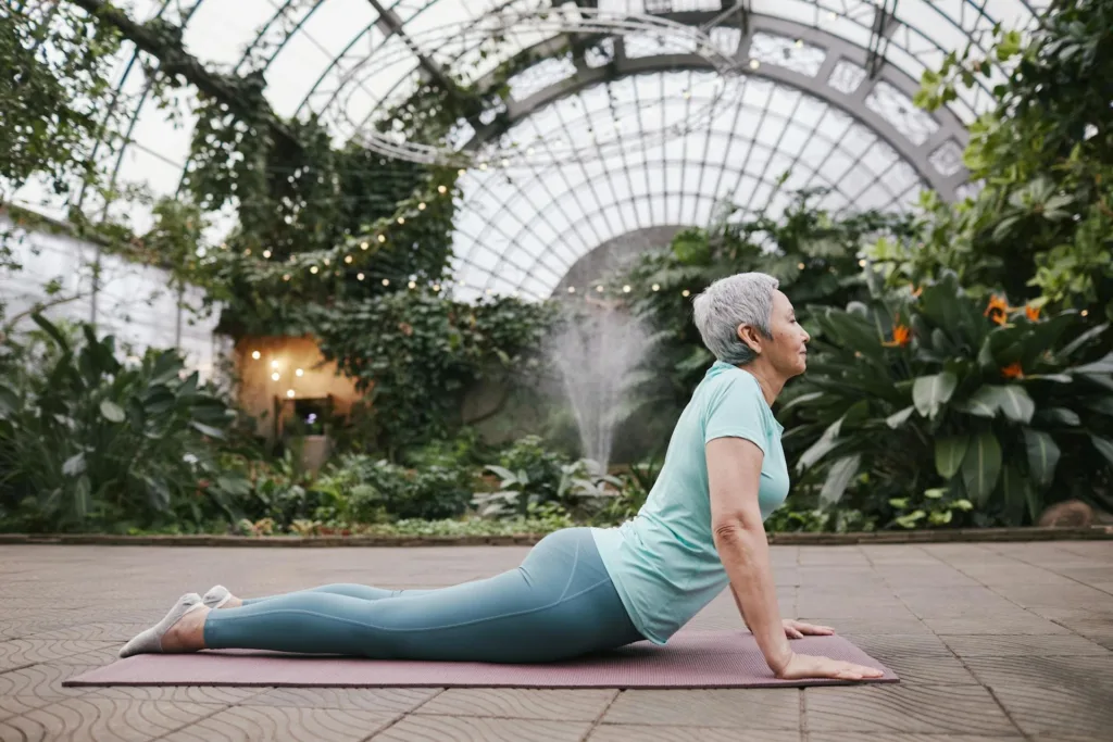 A relaxed looking lady does yoga in an indoor garden