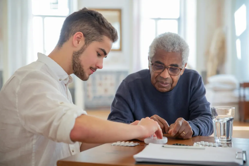 A man assisting a senior with medication