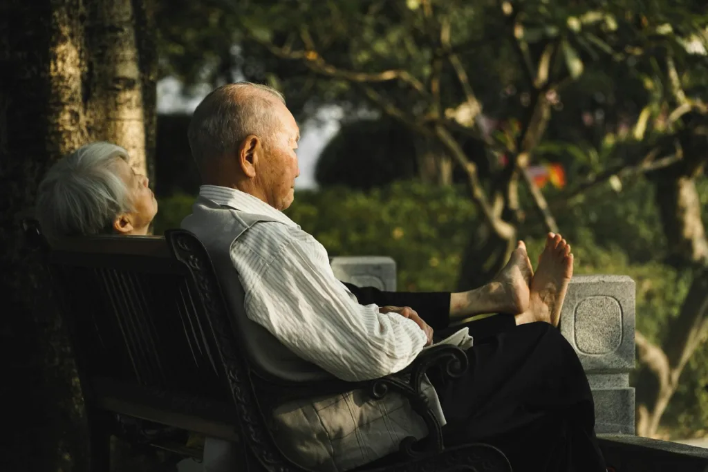 Two seniors relax in porch chairs and look off in the distance