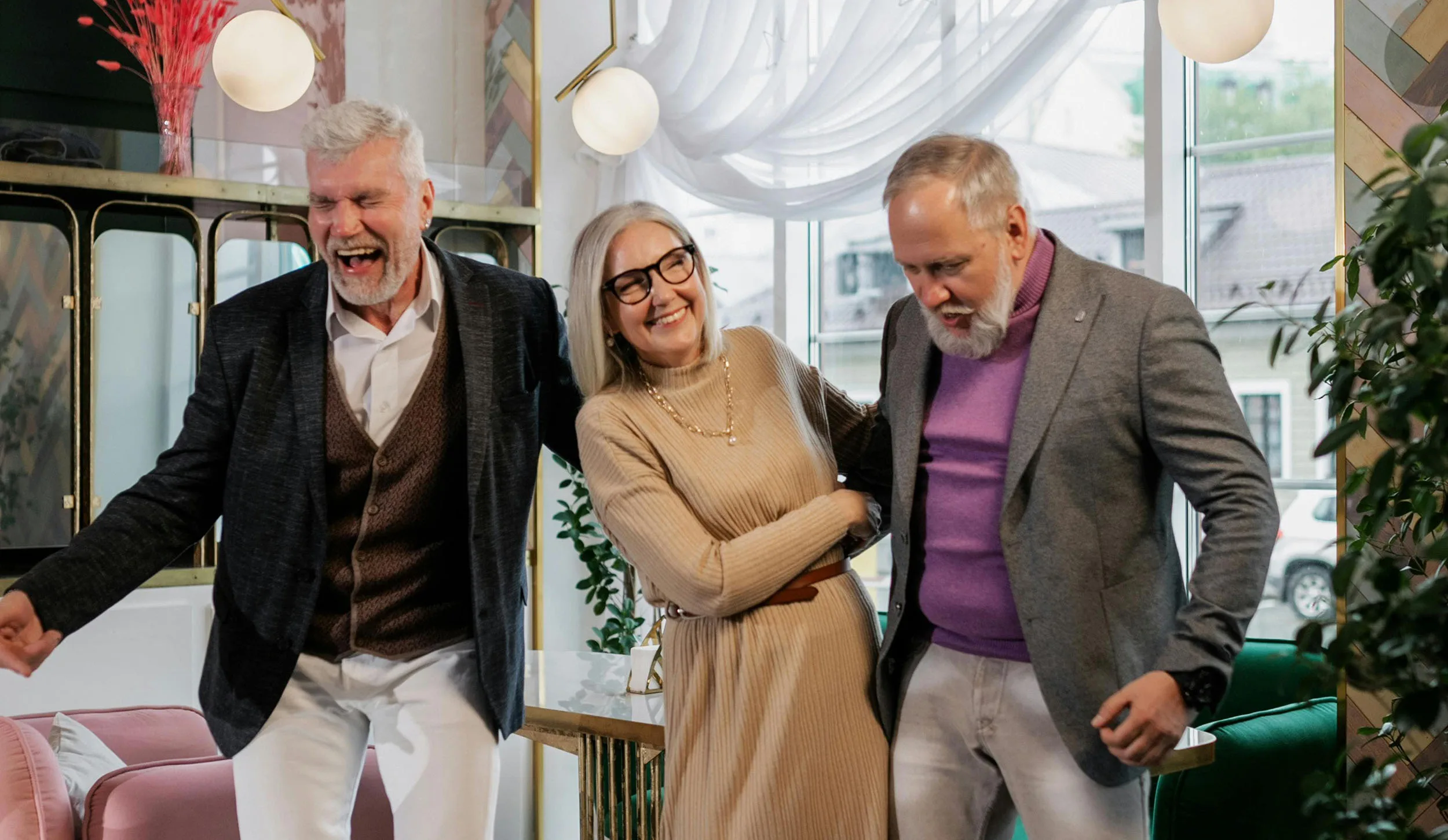 Three seniors dressed elegantly dance and laugh together